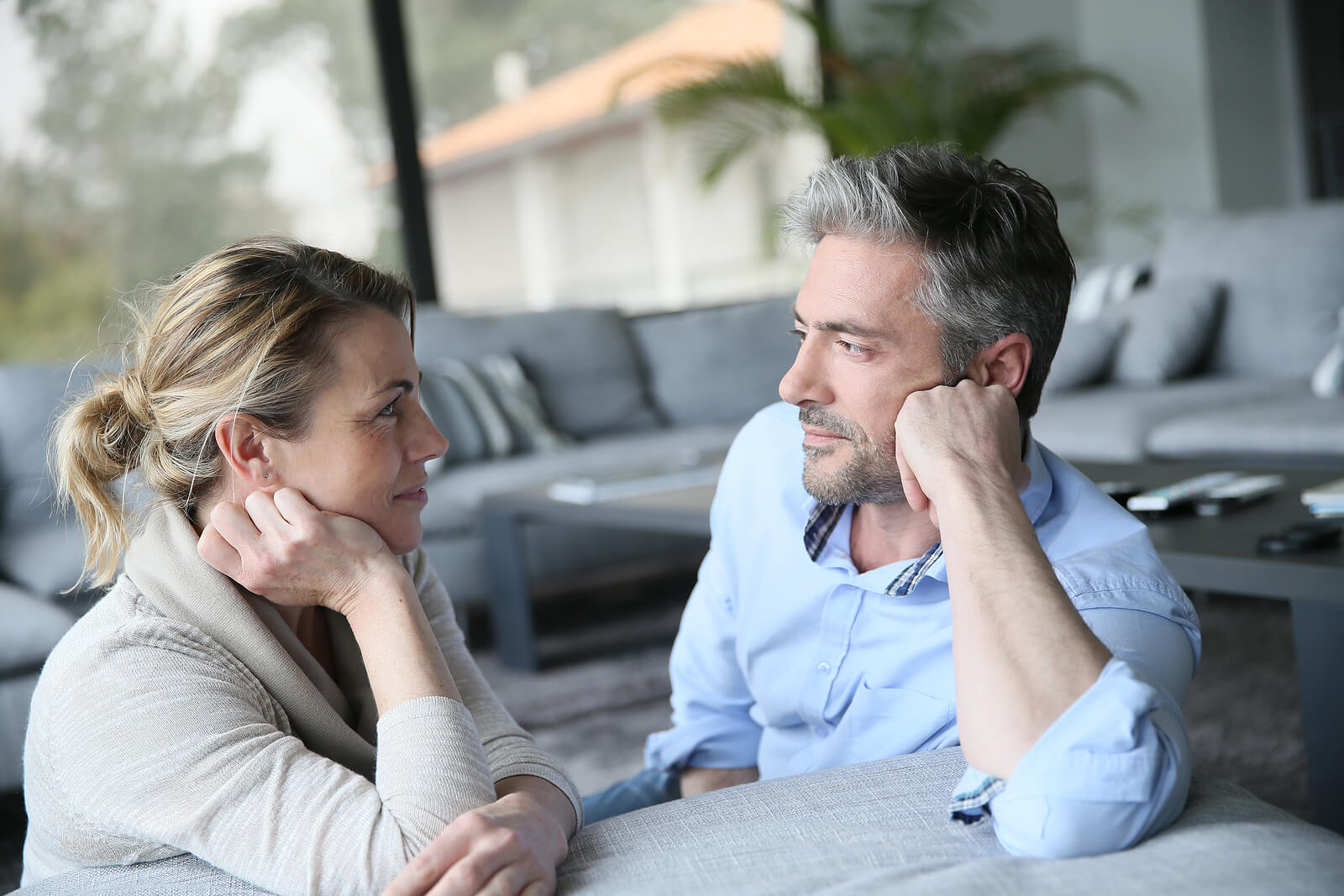 Image of a couple sitting on a couch smiling and looking at one another. If you and your partner feel stuck in unhealthy relationship patters, find support with EMDR therapy in Wake Forest, NC.