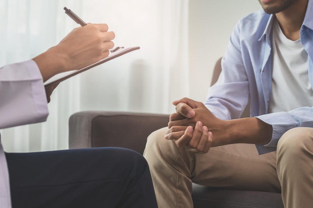 Image of a man talking to someone writing on a clipboard. Find support when it comes to healing from your anxiety, depression, and more with the help of EMDR therapy in Raleigh, NC.