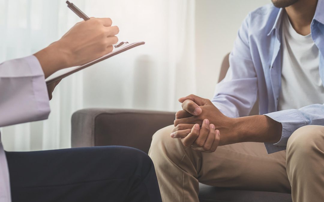 Image of a man talking to someone writing on a clipboard. Find support when it comes to healing from your anxiety, depression, and more with the help of EMDR therapy in Raleigh, NC.