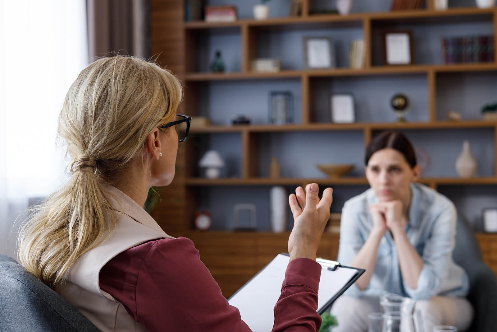 Over the shoulder image of a woman therapist sitting across from another woman talking. Discover how EMDR therapy in Raleigh, NC can help you begin healing from unresolved trauma. Find support soon with EMDR therapy for PTSD.