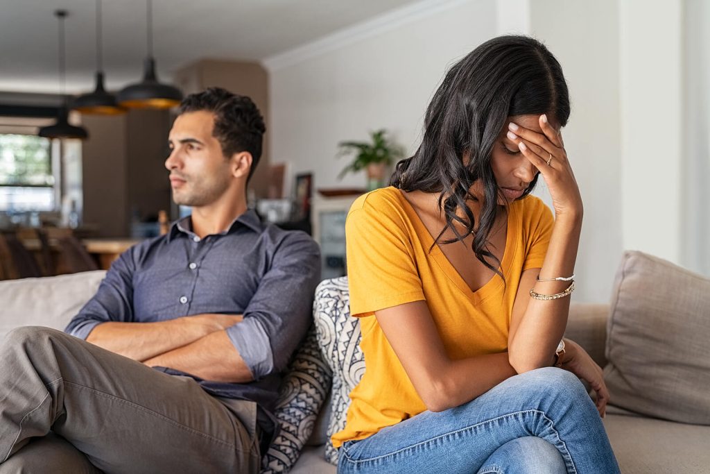 Image of an upset couple sitting on a couch separated. Heal from the trauma that affects your relationship with the help of couples EMDR therapy in Raleigh, NC.