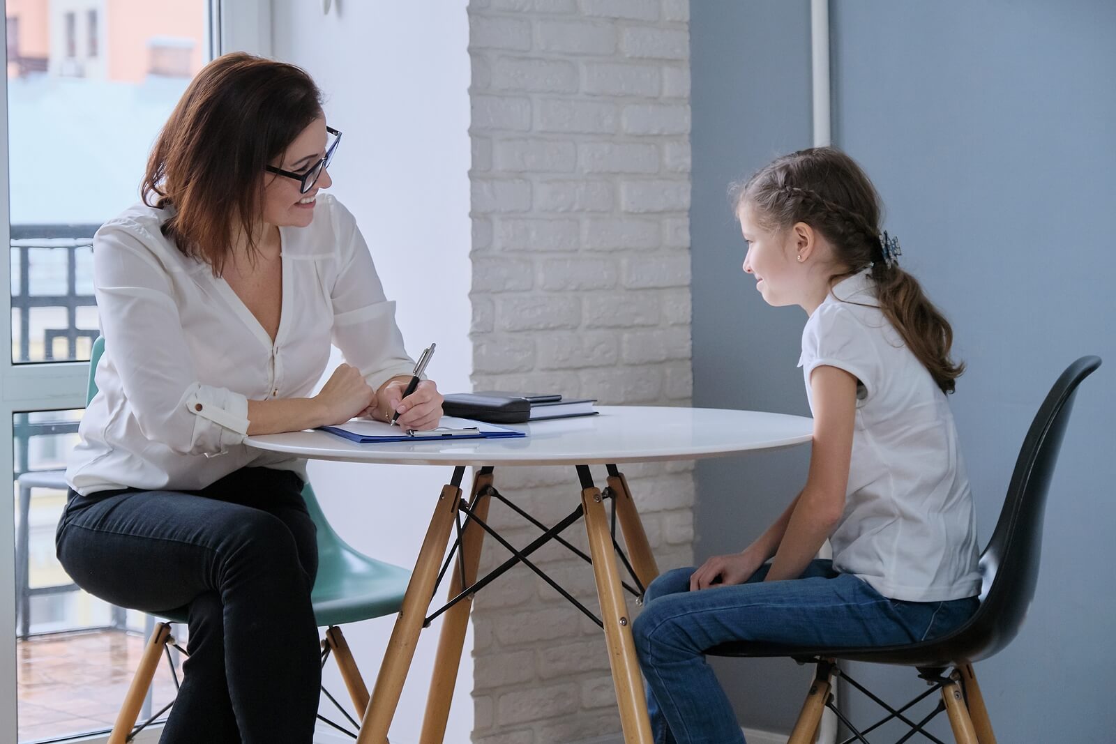 Image of a little girl sitting at a table receiving support from an EMDR therapist to help overcome anxiety. EMDR therapy in Raleigh, NC can help your child begin to heal from their anxiety and start thriving in their life.