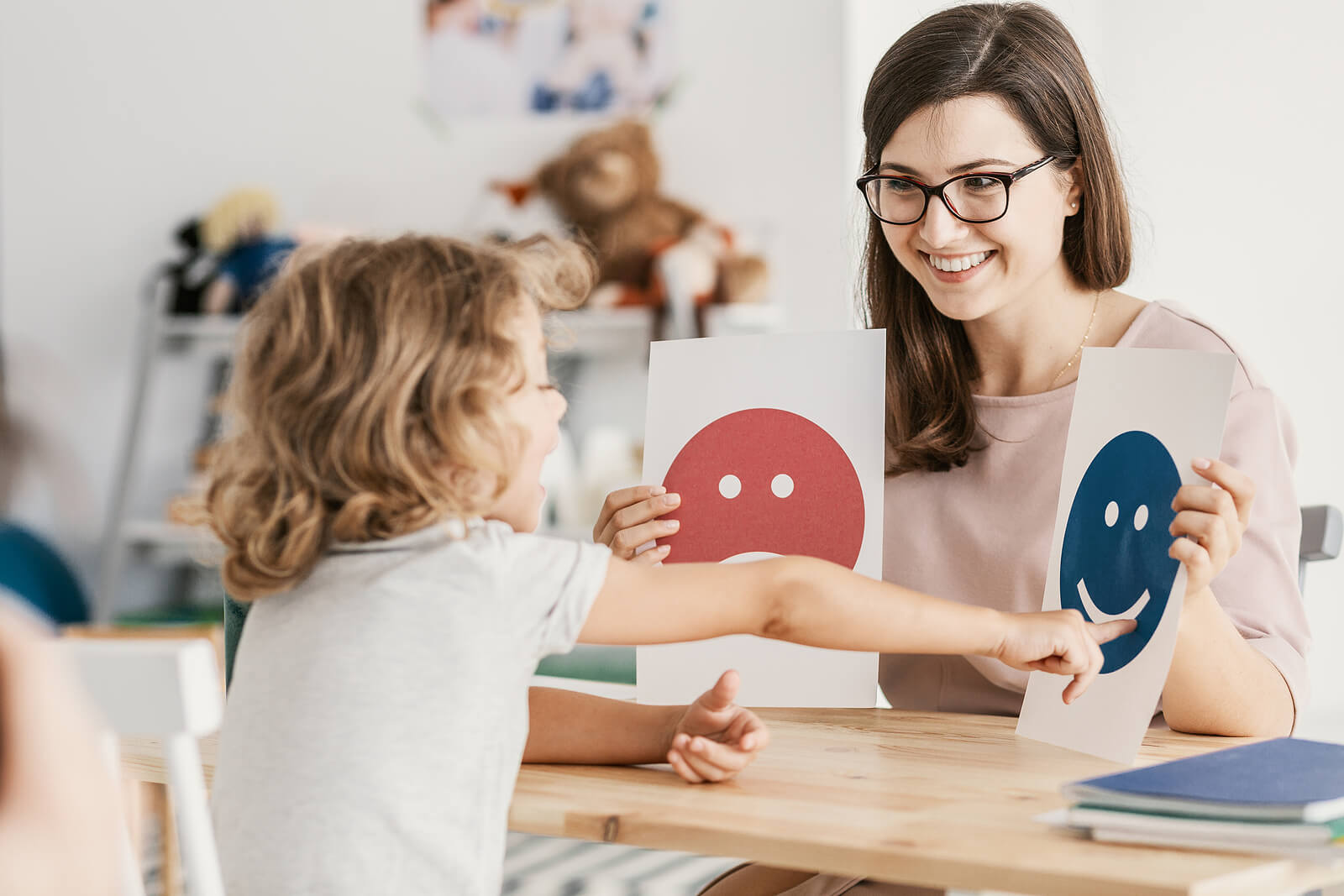 boy in therapy | emdr therapy in raleigh, nc | emdr therapist in raleigh, nc | emdr therapy for children | emdr and children | 27617 | 27596 | 27616 Image of a young boy sitting at a table pointing at emotions on paper with a therapist. With EMDR therapy in Raleigh, NC you can see positive changes in your child's emotions as they begin to process their unresolved trauma.