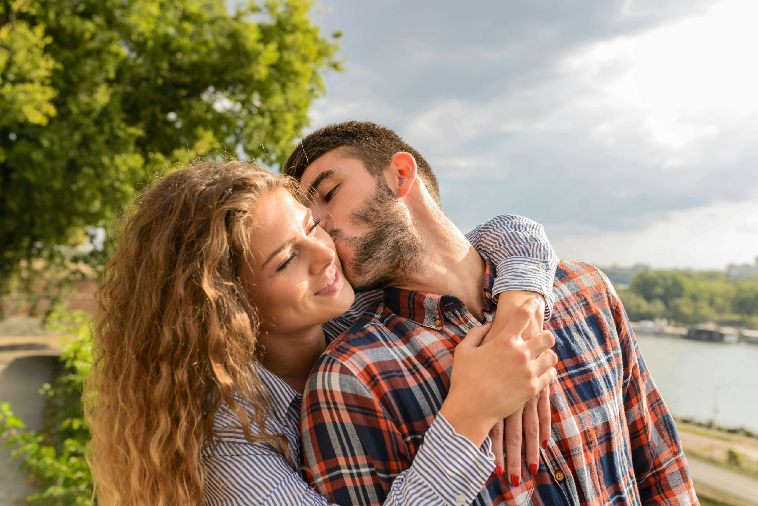 happy couple kissing | emdr therapy in raleigh, nc | emdr therapist | emdr therapy for couples | emdr trauma therapy | 27616 27609 | 27604 Image of a woman smiling as a man kisses her cheek. Begin healing from trauma in your relationship caused by infidelity or betrayal with EMDR therapy in Raleigh, NC.
