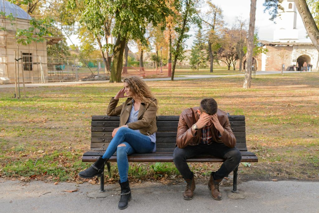 Image of an upset couple sitting apart on a bench in a park. With the support of a compassionate EMDR therapist in Raleigh, NC you and your partner can begin to heal after betrayal.
