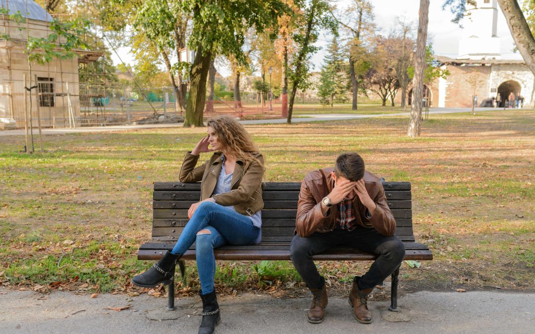 Image of an upset couple sitting apart on a bench in a park. With the support of a compassionate EMDR therapist in Raleigh, NC you and your partner can begin to heal after betrayal.