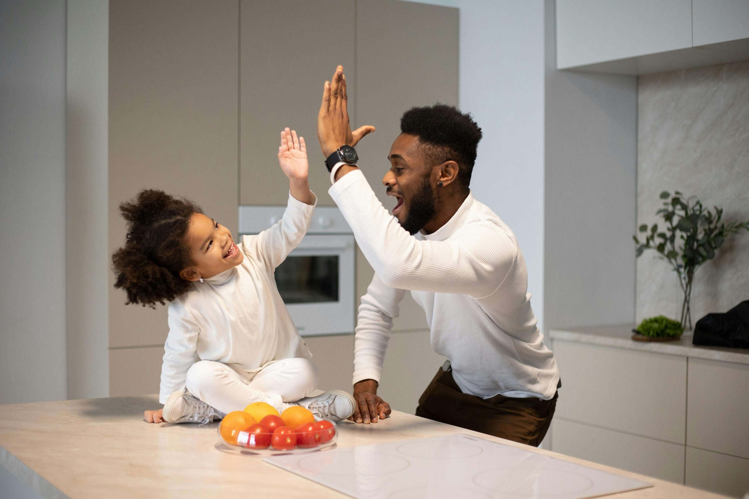 happy father and daughter | emdr therapy in raleigh, nc | emdr therapist | emdr for childhood trauma | emdr childhood trauma | Five Points | Boylan Heights | Brier Creek | Raleigh Happy father and daughter in the kitchen high-fiving. If you struggle with generational trauma and are looking to heal and create a new path forward, find support with EMDR therapy in Raleigh, NC.